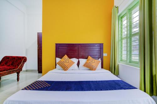 a bedroom with a bed and a yellow wall at Hotel O Dream Palace in Kovalam