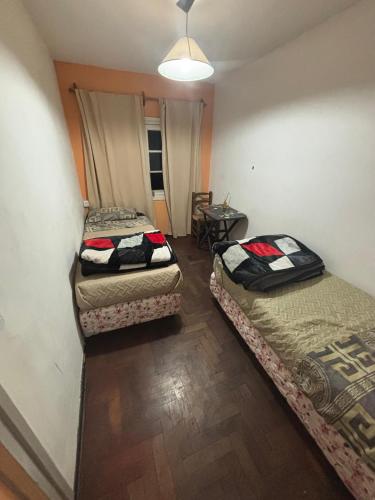 three beds in a small room with a table at Hostel Urqu Ñan in Mendoza