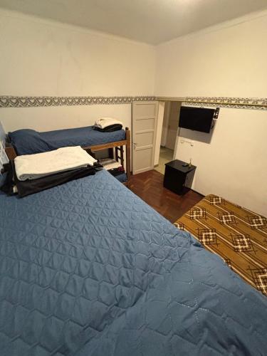 a bedroom with two beds and a flat screen tv at Hostel Urqu Ñan in Mendoza