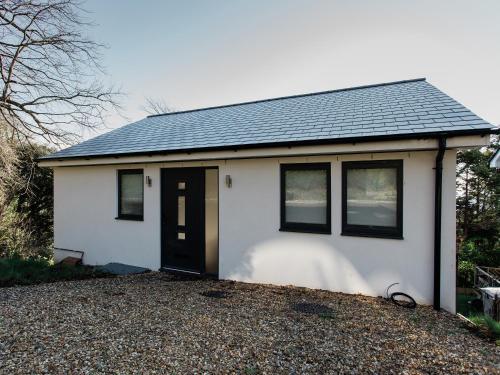 una pequeña casa blanca con una puerta negra en Inglewood Retreat, en Saint Lawrence