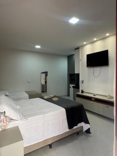 a bedroom with a large bed and a flat screen tv at Suíte Viva o Paraíso in Camocim
