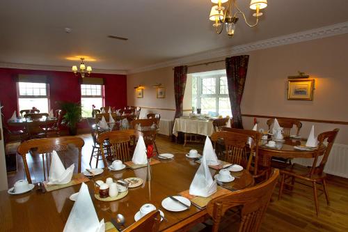un restaurante con mesas de madera y sillas con servilletas. en Woodlawn House, en Killarney