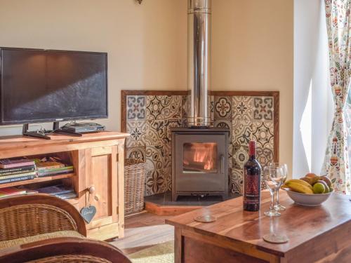 a living room with a fireplace and a table with a television at Welshouse in Henllan
