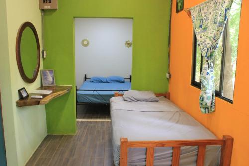 two beds in a room with green and orange walls at Avellanas Surf Hostel in Playa Avellana