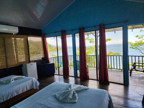 a room with two beds and a view of the ocean at Cabinas La Parcela in Dominicalito