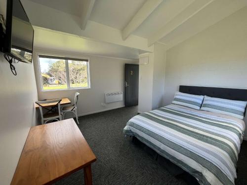 ein Schlafzimmer mit einem Bett und einem Tisch und einem Fenster in der Unterkunft Te Tihi Noho Shared Accommodation 