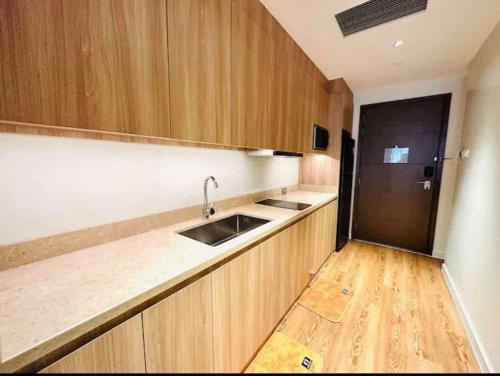 a kitchen with wooden cabinets and a sink and a refrigerator at Novotel Executive Suite - Acqua Manila Khendra in Manila