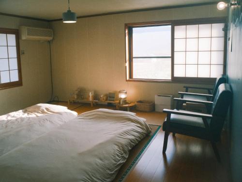 a bedroom with a bed and a chair and a window at 泊まれる本屋 まるとしかく in Mima