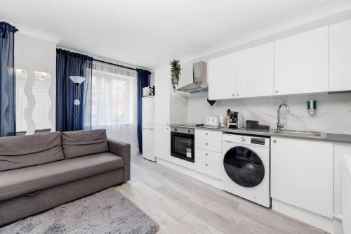 a living room with a couch and a kitchen at Parkside Studio Retreat, 5 min from station ,R2 in London