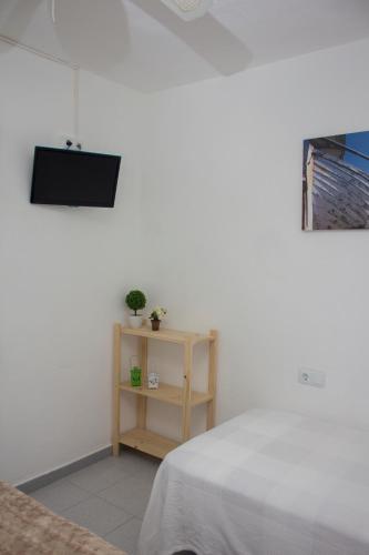 a bedroom with a bed and a table with a tv at Apartamentos Calypso in Punta Umbría