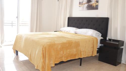 a bedroom with a bed with a yellow blanket on it at Villa Venecia in La Ceiba