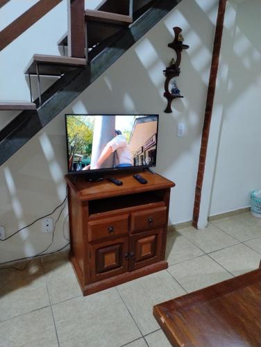 a flat screen tv sitting on a wooden entertainment center at Casa Duplex de Condomínio no Peró - Cabo Frio in Cabo Frio