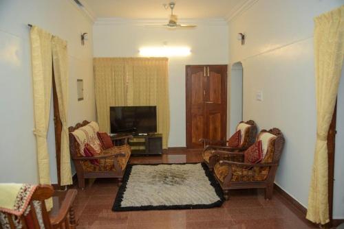 a living room with chairs and a flat screen tv at Amrutham Homestay in Trivandrum