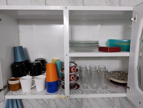 a white cabinet filled with cups and dishes at Casa Duplex de Condomínio no Peró - Cabo Frio in Cabo Frio