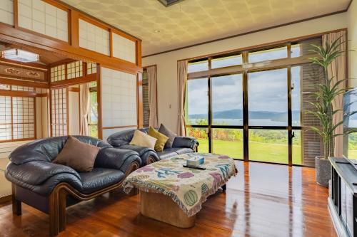 a living room with a leather couch and a coffee table at Ocean View House Nakijin in Nakijin
