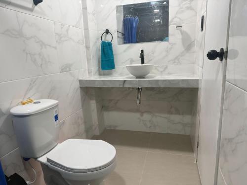 a white bathroom with a toilet and a sink at Casa Fama in San Andrés