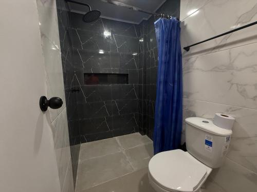 a bathroom with a toilet and a shower with a blue shower curtain at Casa Fama in San Andrés