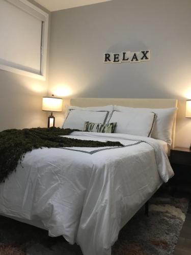 a bedroom with a white bed with two lamps at Almost Heaven - Cozy 2BDRM APT near Heritage Park,Spruce Meadows & Banff-SW Calgary in Calgary