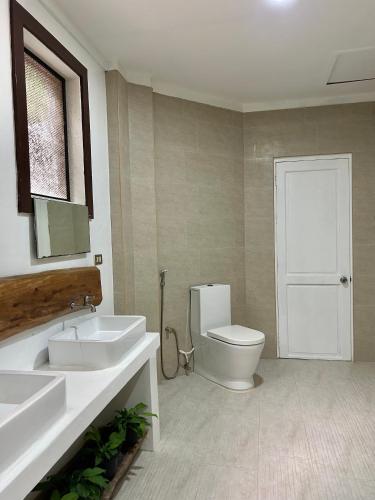 a bathroom with a toilet and a sink and a mirror at Castle View Hotel Samal in Magamomo