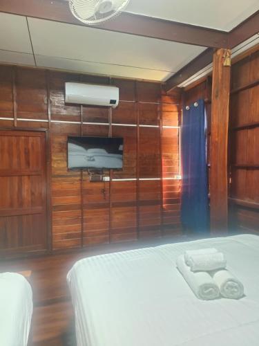 a bedroom with a bed and a tv on the wall at Terracotta de Poterie in Sukhothai