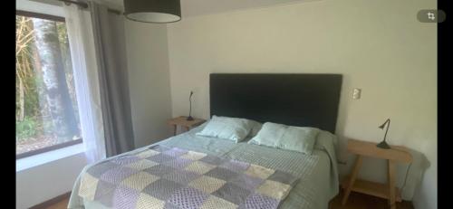 a bedroom with a bed with a checkered blanket and a window at Casa campo en plena naturaleza 3 dormitorios y 2 baños in Lago Ranco