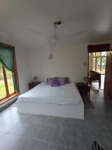a bedroom with a white bed with purple pillows at Wasini house mkwiro village in Shimoni