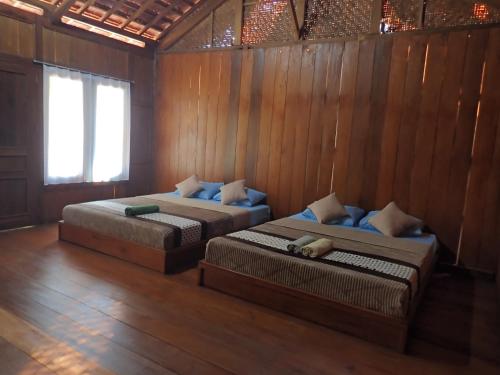 two beds in a room with wooden walls at JN Cottage dan Camping Ground in Karimunjawa