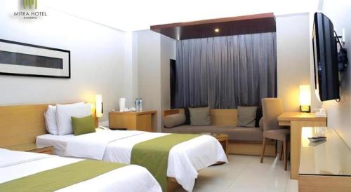 a hotel room with two beds and a couch at Mitra Bandung Hotel in Bandung