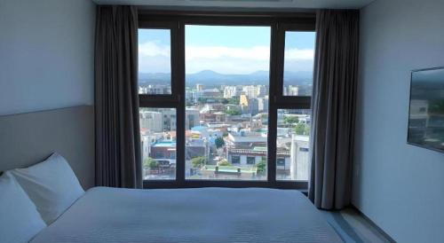 a bedroom with a window with a view of a city at Ebenezer Hotel in Jeju