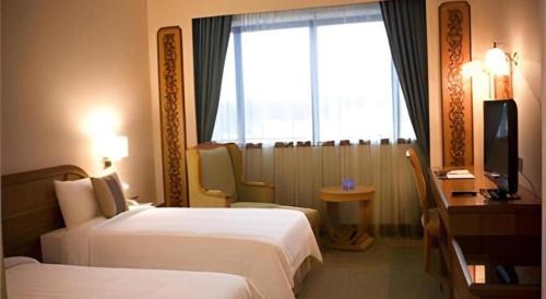 a hotel room with two beds and a desk and a window at The CentrePoint Hotel in Bandar Seri Begawan