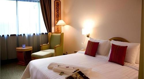 a hotel room with a large bed and a chair at The CentrePoint Hotel in Bandar Seri Begawan