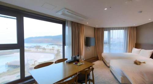 a hotel room with two beds and a desk and a window at Ebenezer Hotel in Jeju
