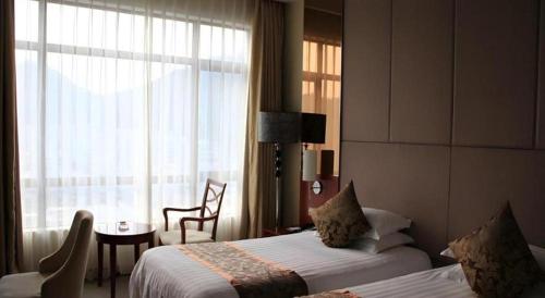 a hotel room with two beds and a window at New Century Hangzhou Qiandao Lake Longting Hotel in Thousand Island Lake