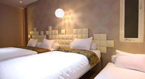 a bedroom with two beds with white sheets at Griya Jogja Hotel in Yogyakarta