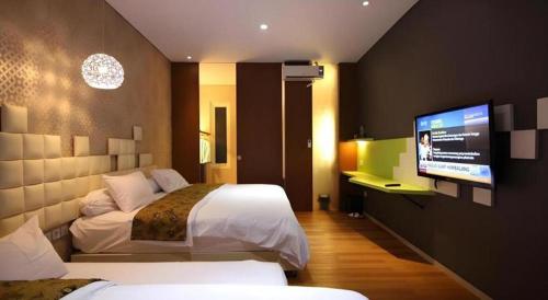 a hotel room with two beds and a flat screen tv at Griya Jogja Hotel in Yogyakarta