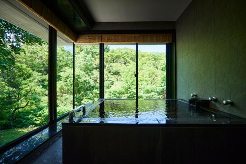 a bathroom with a tub with a large window at Chalet Ivy Jozankei in Jozankei