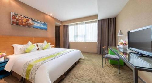 a hotel room with a large bed and a flat screen tv at Catic Hotel--Adjacent Buliding in Zhuhai
