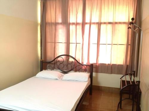 a bed in a room with a window and a bed with white sheets at Numsin Hotel in Ratchaburi
