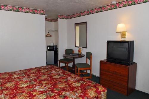 ein Hotelzimmer mit einem Bett und einem TV in der Unterkunft Stone Inn Extended Stay U of A in Tucson