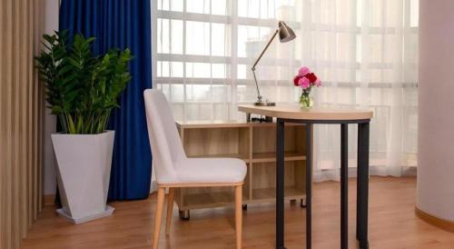 a desk with a chair and a lamp and a vase of flowers at danfeng kelly hotel in Shenzhen