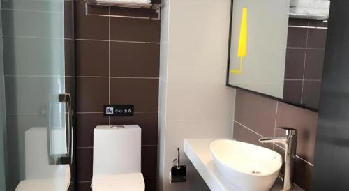 a bathroom with a sink and a toilet and a mirror at IU Hotel Kunming Jinma Bijifang Joy City in Kunming