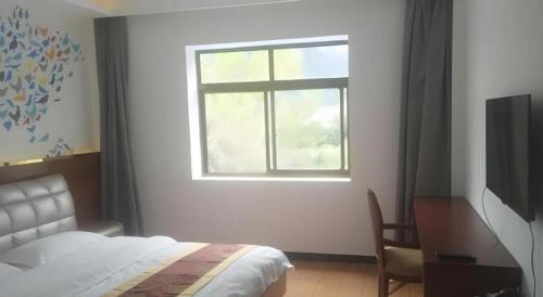 a bedroom with a bed and a desk and a window at Shell Linzhi Bayi Area G318 Shuangyong Road Hotel in Nyingchi