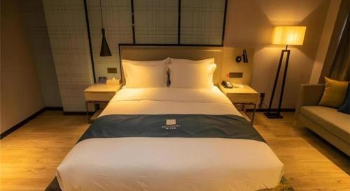 a bedroom with a large bed and a couch at Echarm Hotel Zibo Gaoqing Zhongcheng Inernational in Zibo