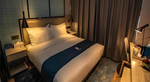 a bedroom with a large bed in a hotel room at Echarm Hotel Zibo Gaoqing Zhongcheng Inernational in Zibo