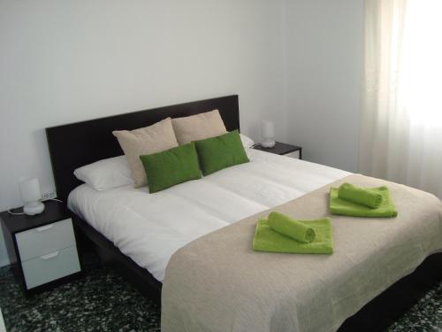 a bedroom with a large bed with green towels on it at El HECHIZO in Seville