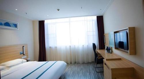 a hotel room with a bed and a desk and a television at City Comfort Inn Yingcheng Railway Station Shanghe Square in Xiaogan