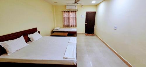 Un dormitorio con una cama grande y una ventana. en Aathidya Lodge, en Ādoni