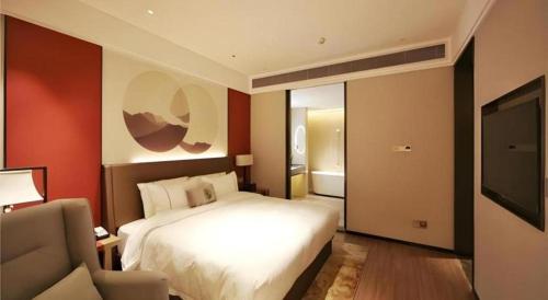 a bedroom with a bed and a couch and a television at E-Cheng Hotel Liuzhou Sanjiang Fengyu Bridge in Sanjiang