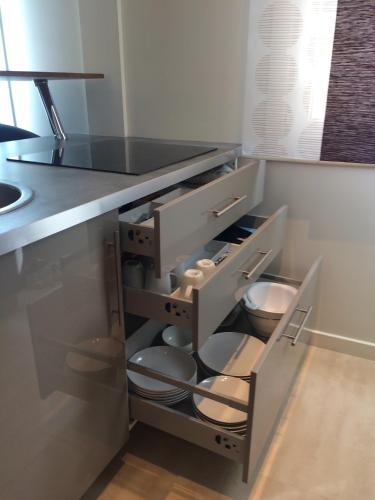 une cuisine avec un tiroir ouvert, des assiettes et des bols dans l'établissement Palme d'hote, à Cannes