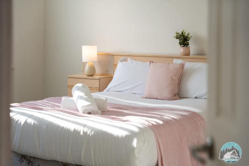a bedroom with a bed with white sheets and pink pillows at Spacious 4 Bedroom House Near Station & Parramatta in Guildford